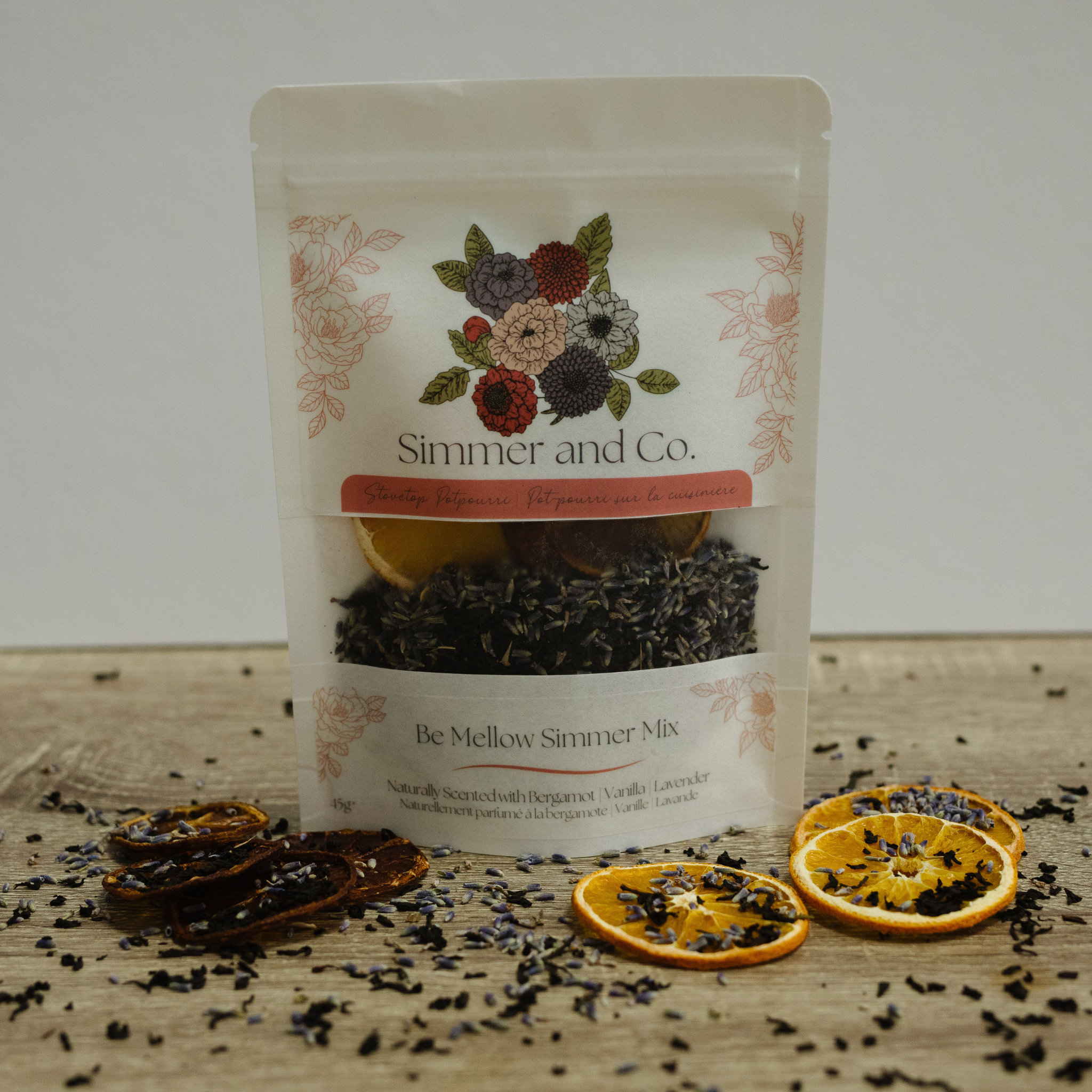 Packaging of 'Simmer and Co.' mellow simmer mix with dried oranges and herbs on a wooden surface.