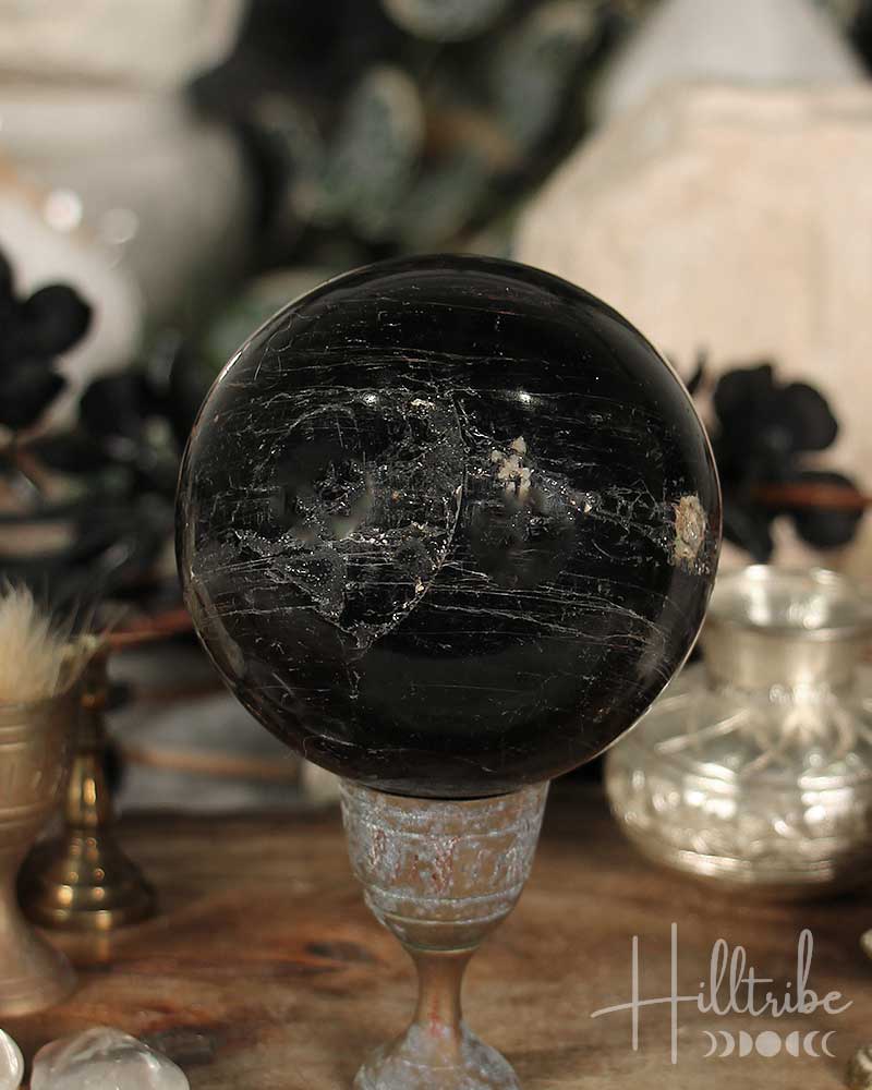 Black Tourmaline sphere on a stand with a blurred background