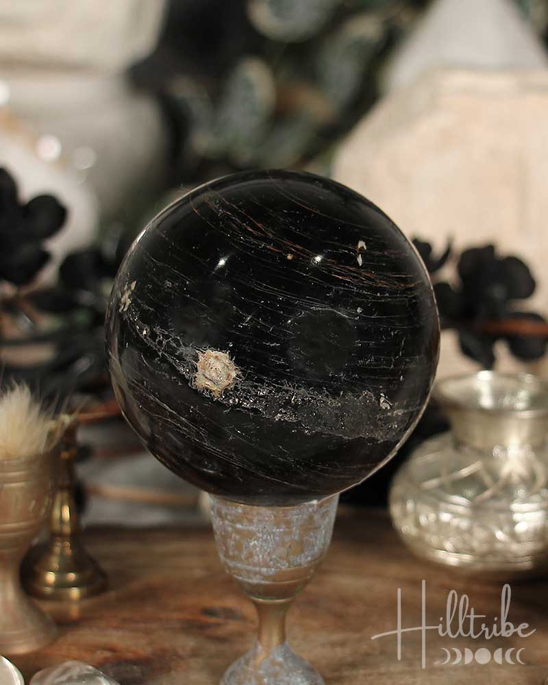 Black Tourmaline sphere on a stand with a blurred background