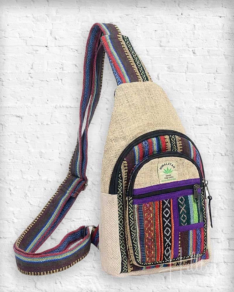 Multicolored sling bag with a textured strap on a white brick wall background