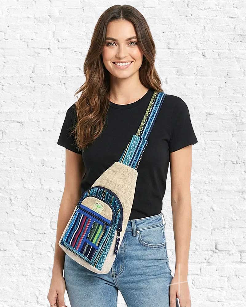 Woman wearing a colorful crossbody bag against a white brick wall