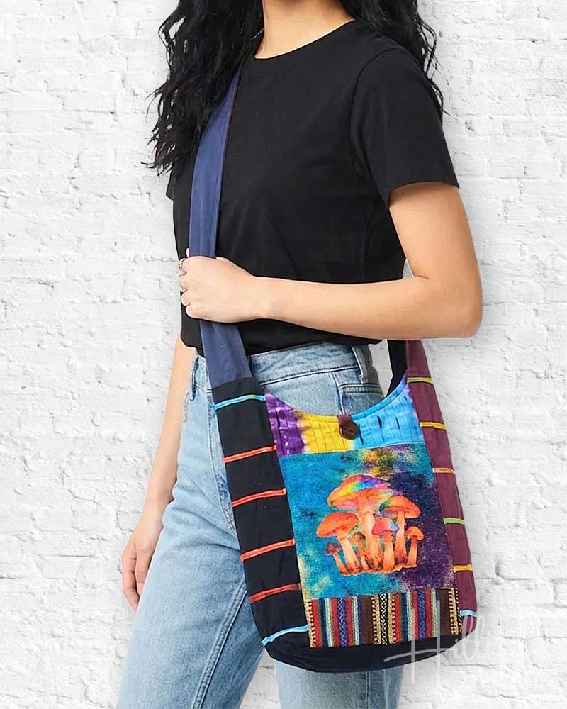 Person holding a colorful bag with mushroom design against a white brick wall