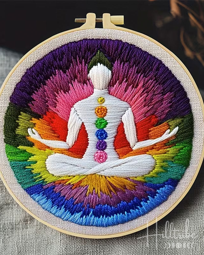 Embroidery hoop with a colorful depiction of a meditating figure and chakra symbols.