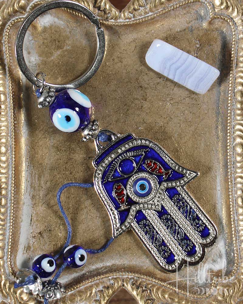 Decorative keychain with Hamsa hand and evil eye charms on a textured surface
