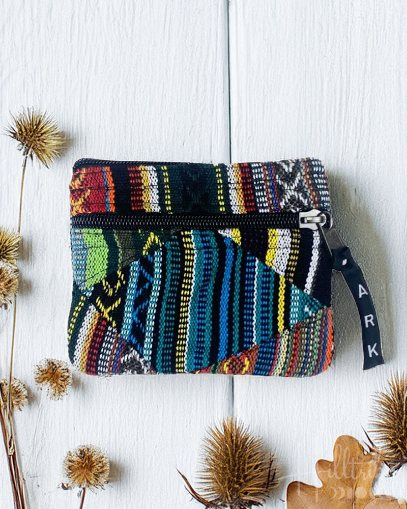 Colorful patterned pouch with a zipper on a white wooden surface with dried plants.