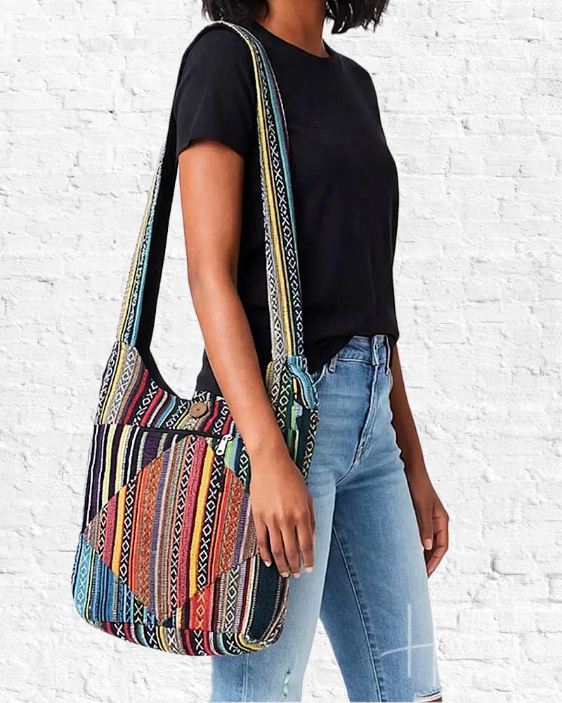 Person wearing a colorful patterned bag against a white brick wall.