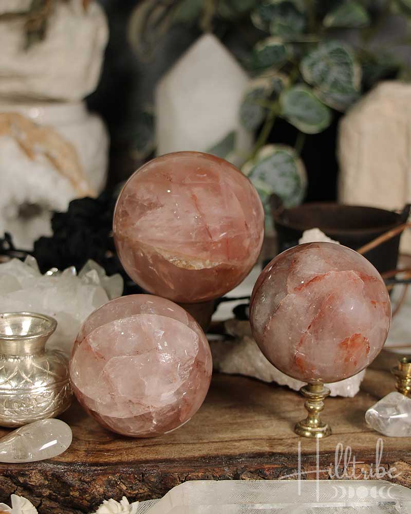 Three Fire Quartz crystal spheres on a wooden surface with blurred background