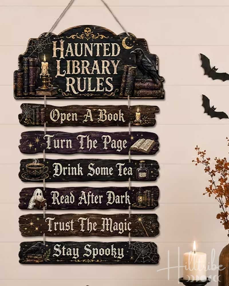 A Halloween-themed wooden hanging sign with the text 'HAUNTED LIBRARY RULES' and nine stacked rules, displayed on a shelf in a decorated room with candles, pumpkins, a house, and bats.