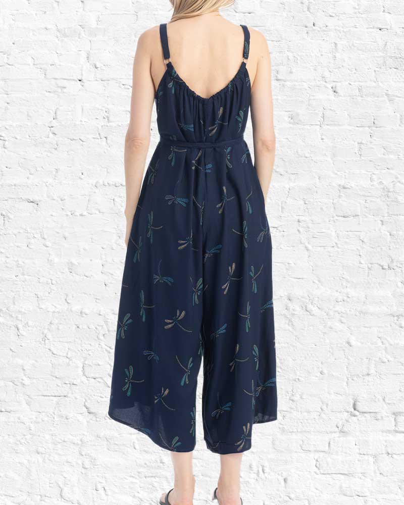Navy blue jumpsuit with floral pattern on a white brick wall background