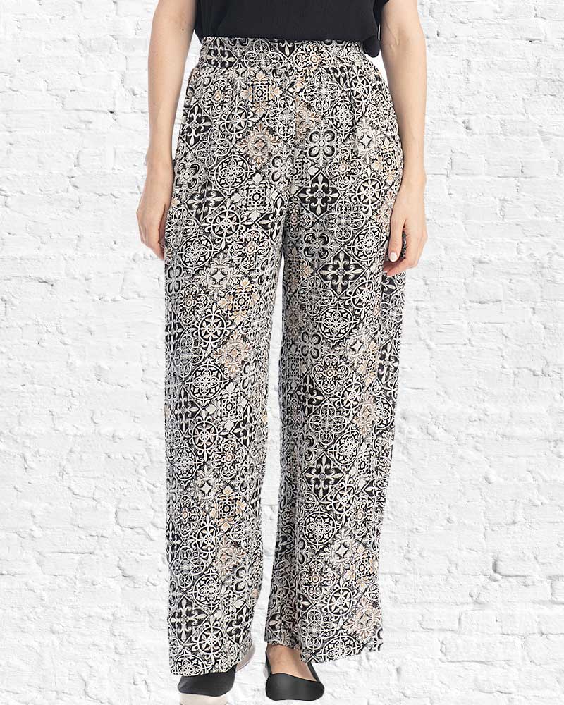 Person wearing patterned pants against a white brick wall