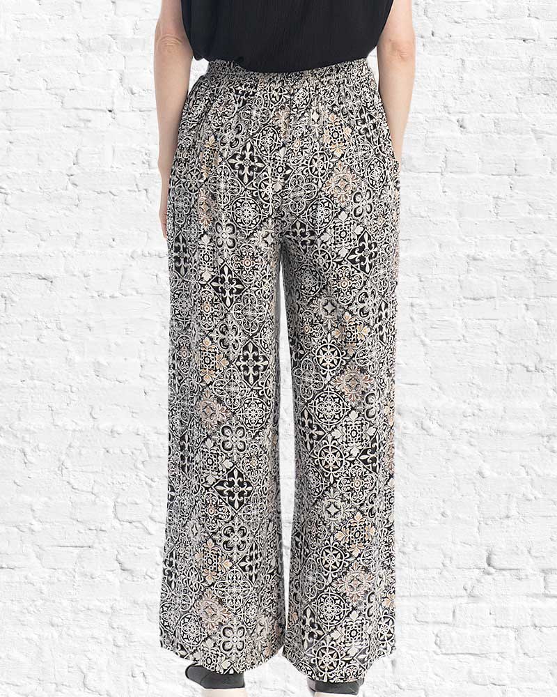 Person wearing patterned pants against a white brick wall.