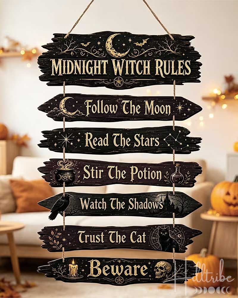 A rustic hanging wooden sign with seven arrow-shaped planks reading 'Midnight Witch Rules' and related phrases, shown in a cozy Halloween-themed living room with pumpkins and string lights.