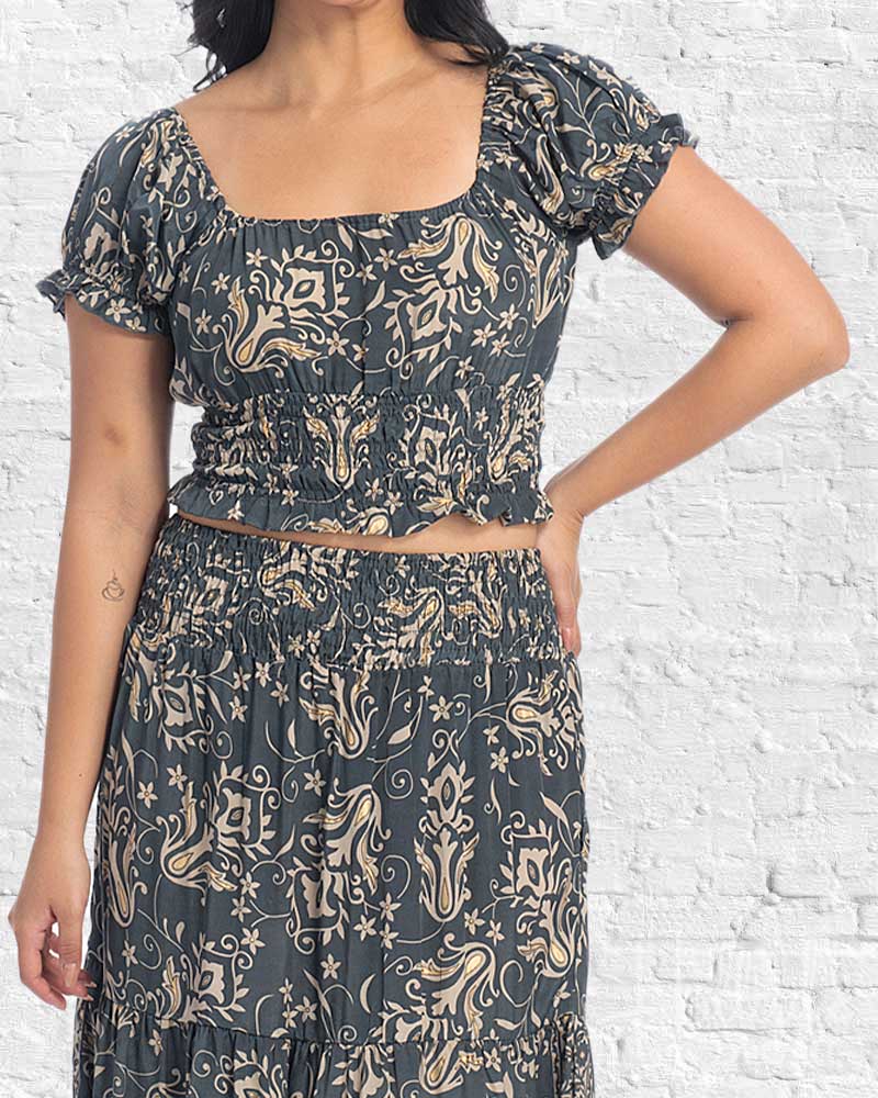 Person wearing a dark patterned outfit against a white brick wall.