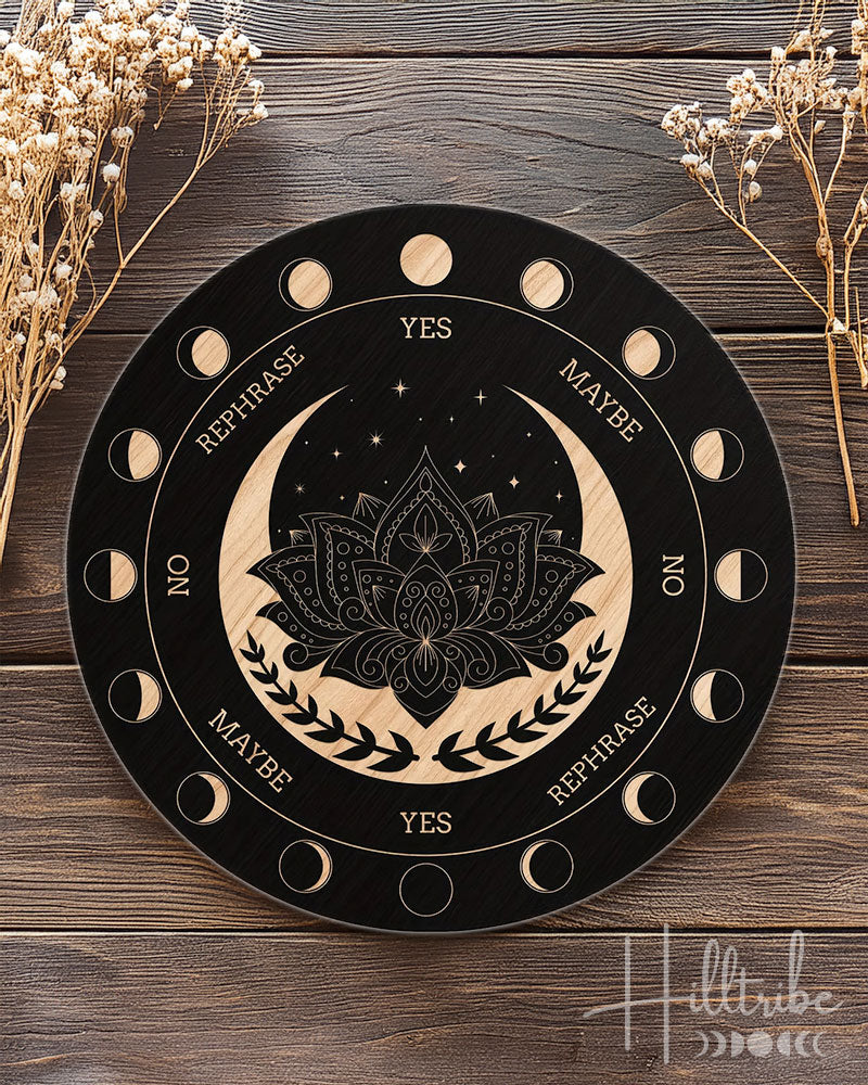 Decorative pendulum board with moon phases and lotus flower design on a wooden surface with dried flowers.