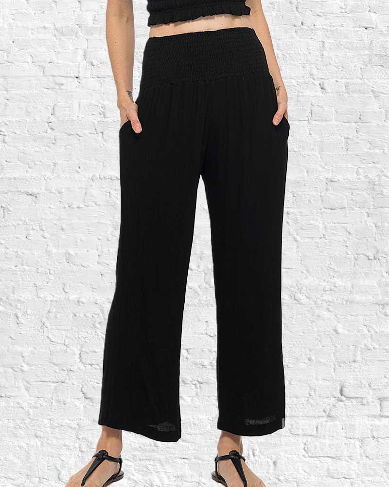 Person wearing black wide-leg pants against a white brick wall.