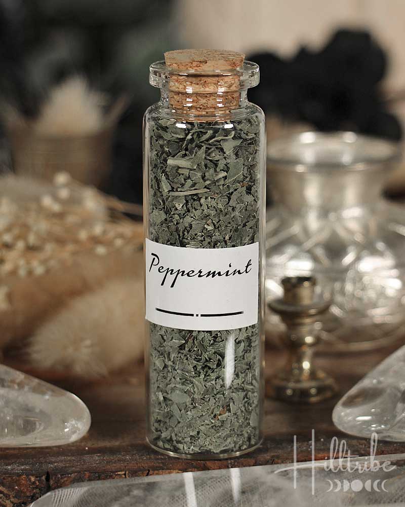 Bottle of peppermint leaves with a cork lid on a wooden surface.
