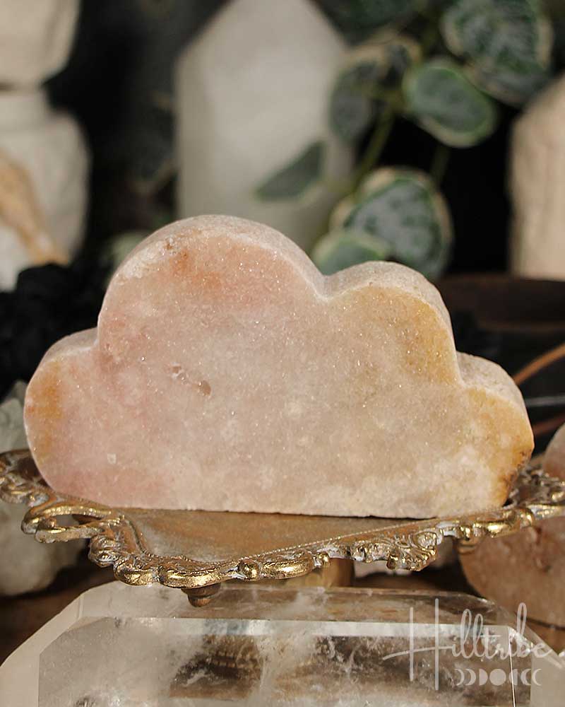 Rose Amethyst cloud-shaped stone on a gold stand with blurred background