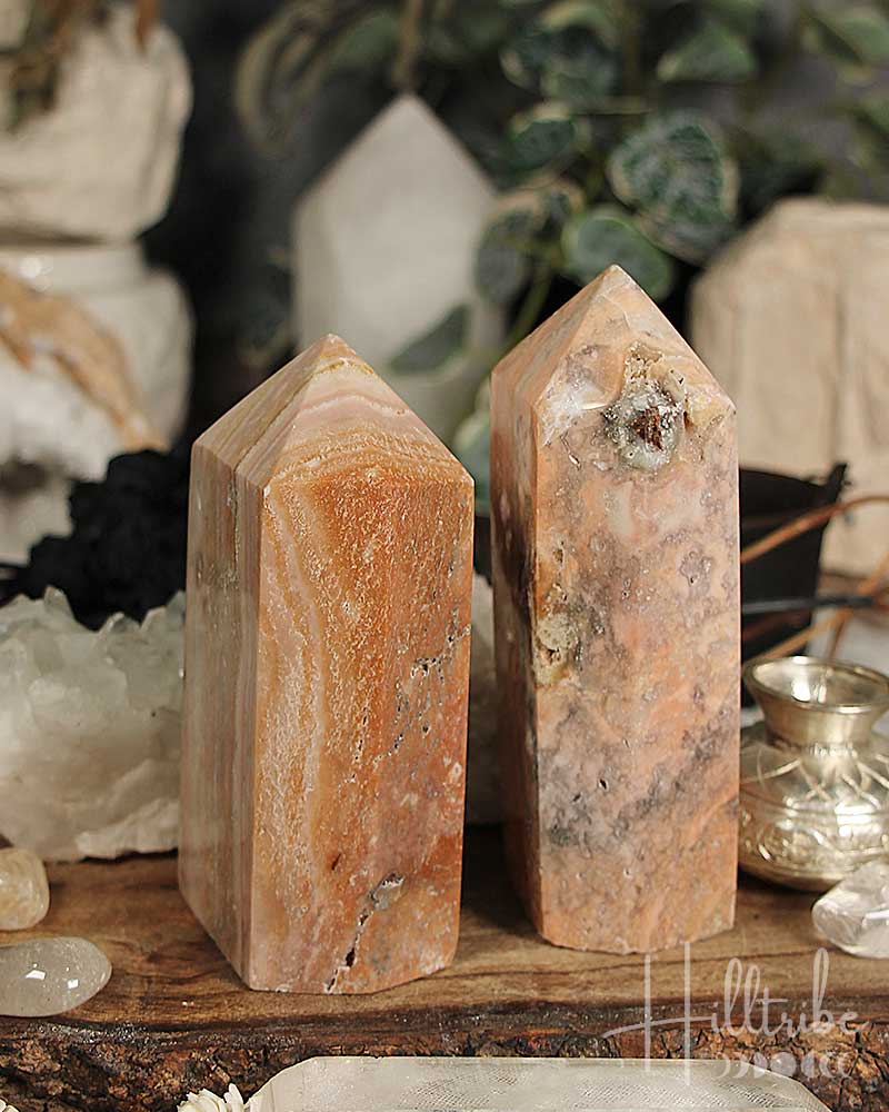 Two Rose Amethyst + Marble Jasper Tower on a wooden surface with a blurred background of decorative items.