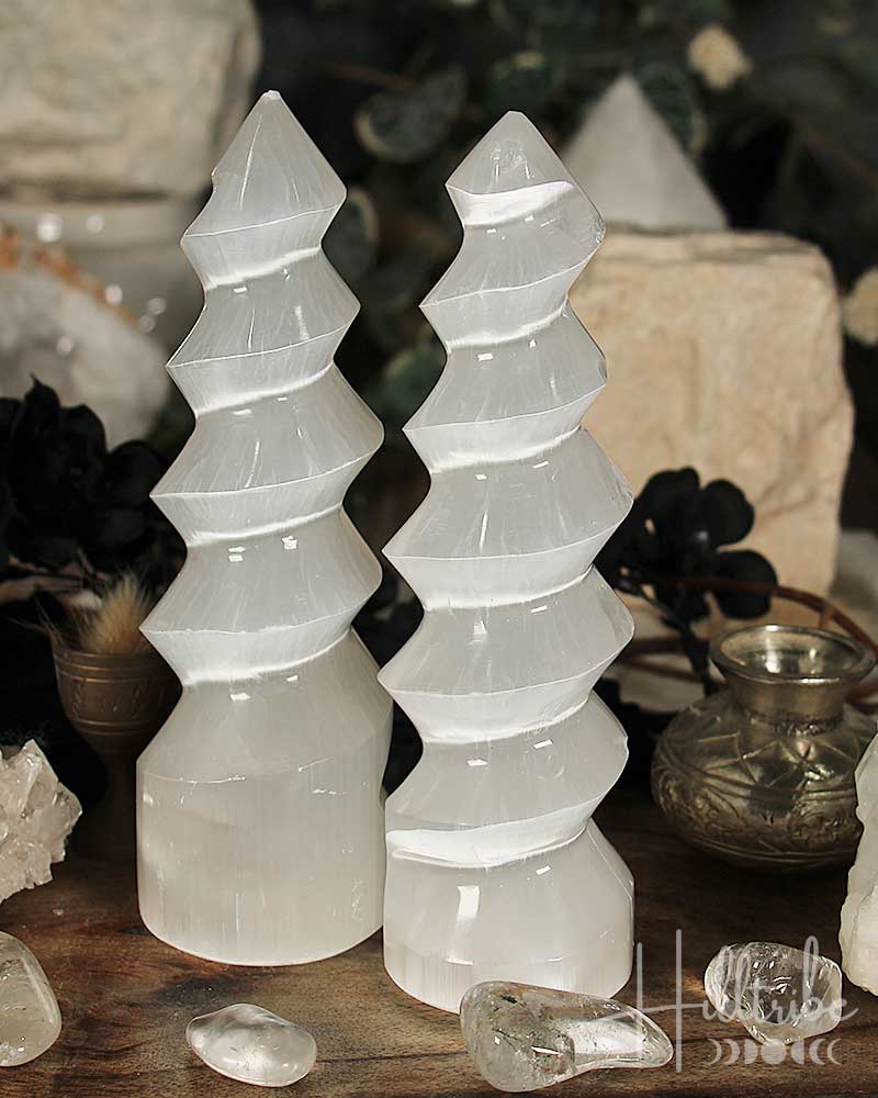 Two selenite crystal towers on a wooden surface with a blurred background