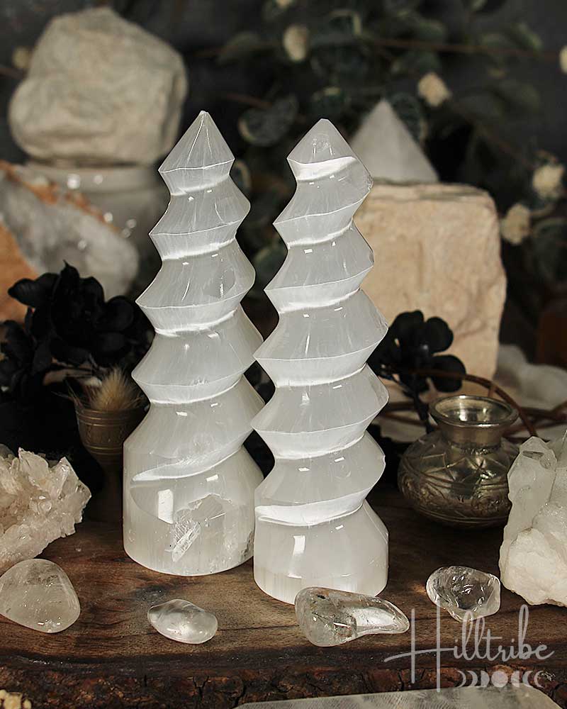 Two selenite crystal towers on a wooden surface with a blurred background