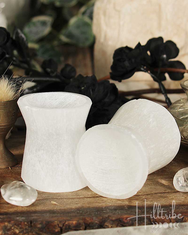 Two selenite stone stands on a wooden surface with decorative elements in the background.