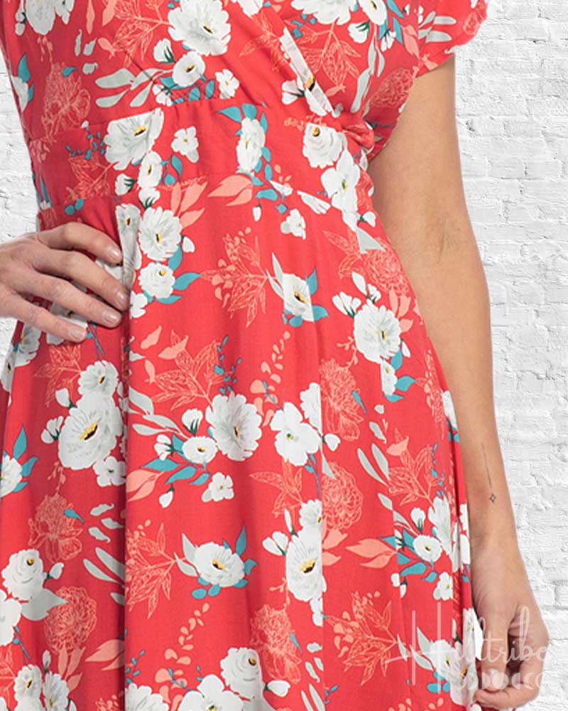 Red floral dress with white flowers on a white brick wall background
