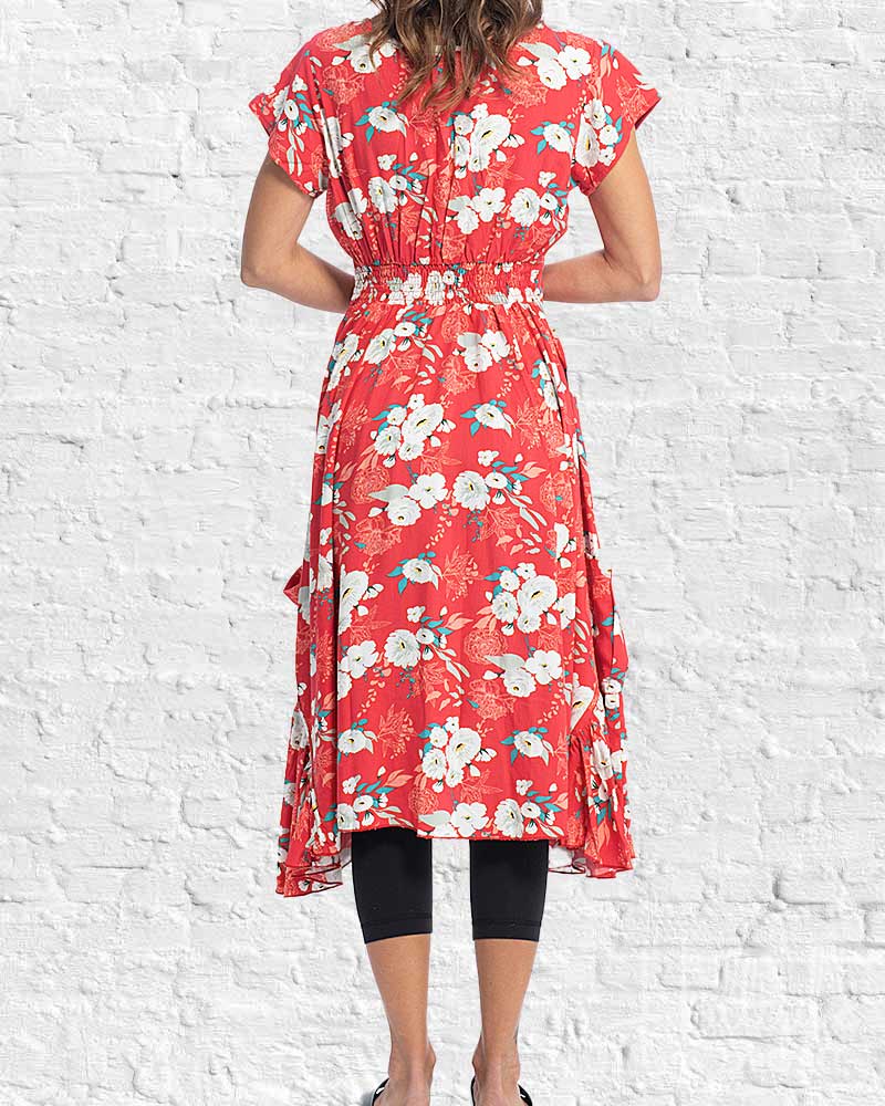 Red floral dress worn by a person against a white brick wall.