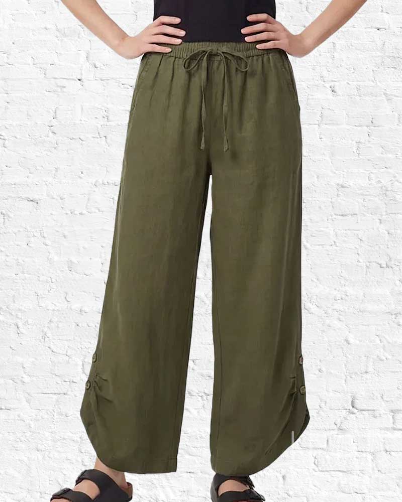 Person wearing olive green wide-leg pants against a white brick wall.