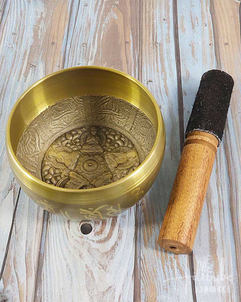 Brass singing bowl with wooden striker on a wooden surface