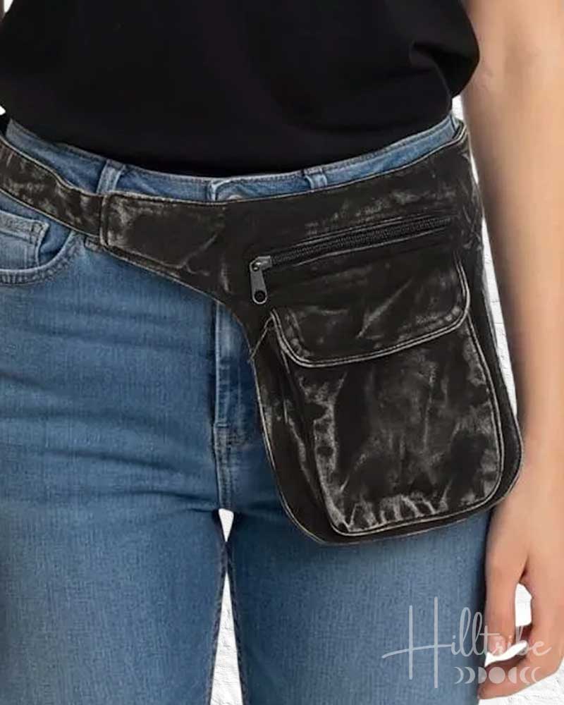 Person wearing a black waist bag with a visible brand logo on a plain background