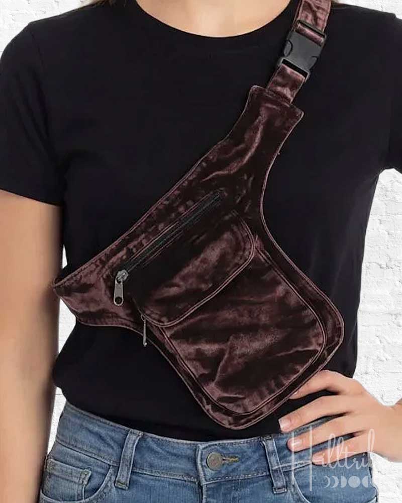 Person wearing a brown velvet crossbody bag with a black shirt and blue jeans.