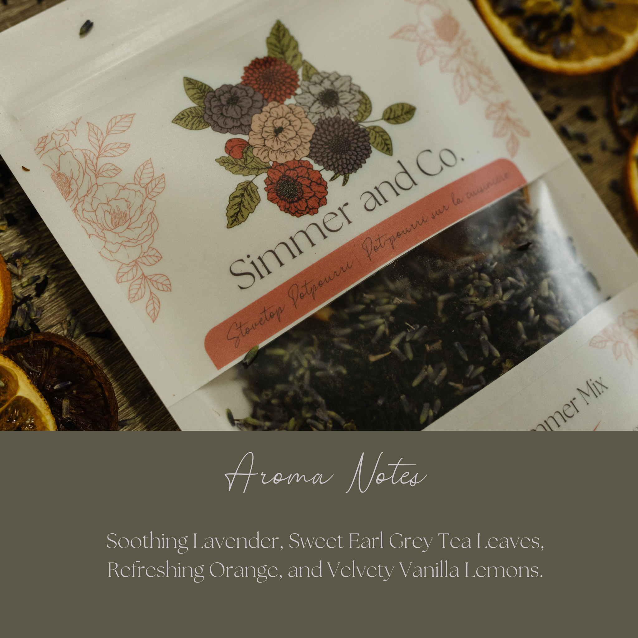 Packaged tea mix with floral label and dried oranges on a dark surface