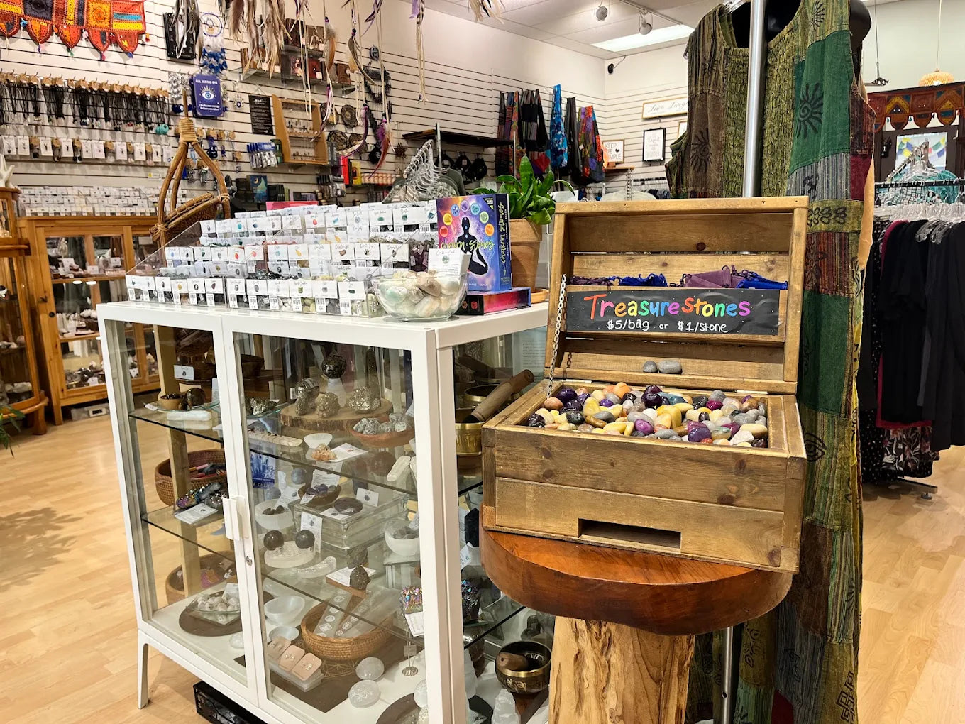 Store interior with a display of small items on a shelf and a wooden crate labeled 'Treasure Stones'.