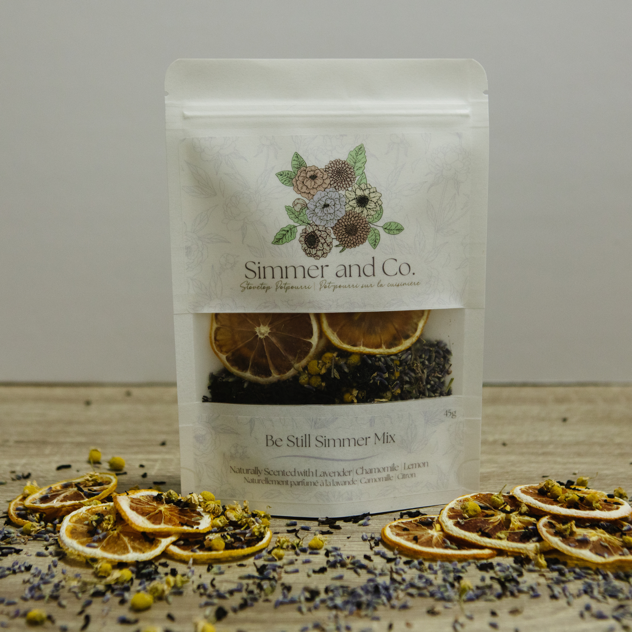 Bag of 'Simmer and Co.' simmer mix with dried fruit and herbs on a wooden surface.