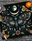 Decorative altar cloth with a moth, moon, and stars design on a dark background.