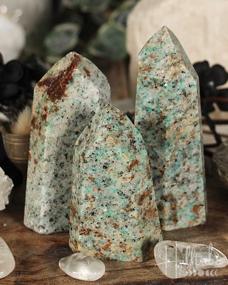 Three amazonite crystal towers on a wooden surface with a blurred background