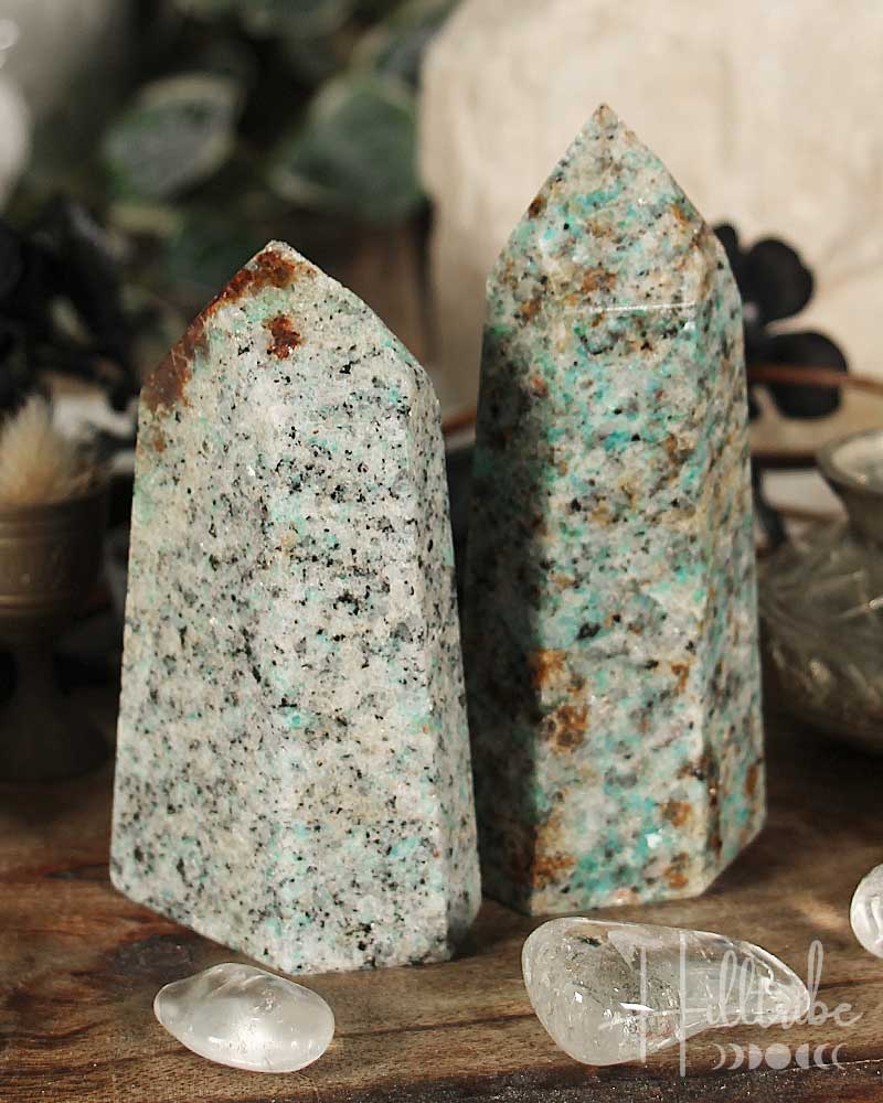 Two amazonite crystal towers on a wooden surface with blurred background