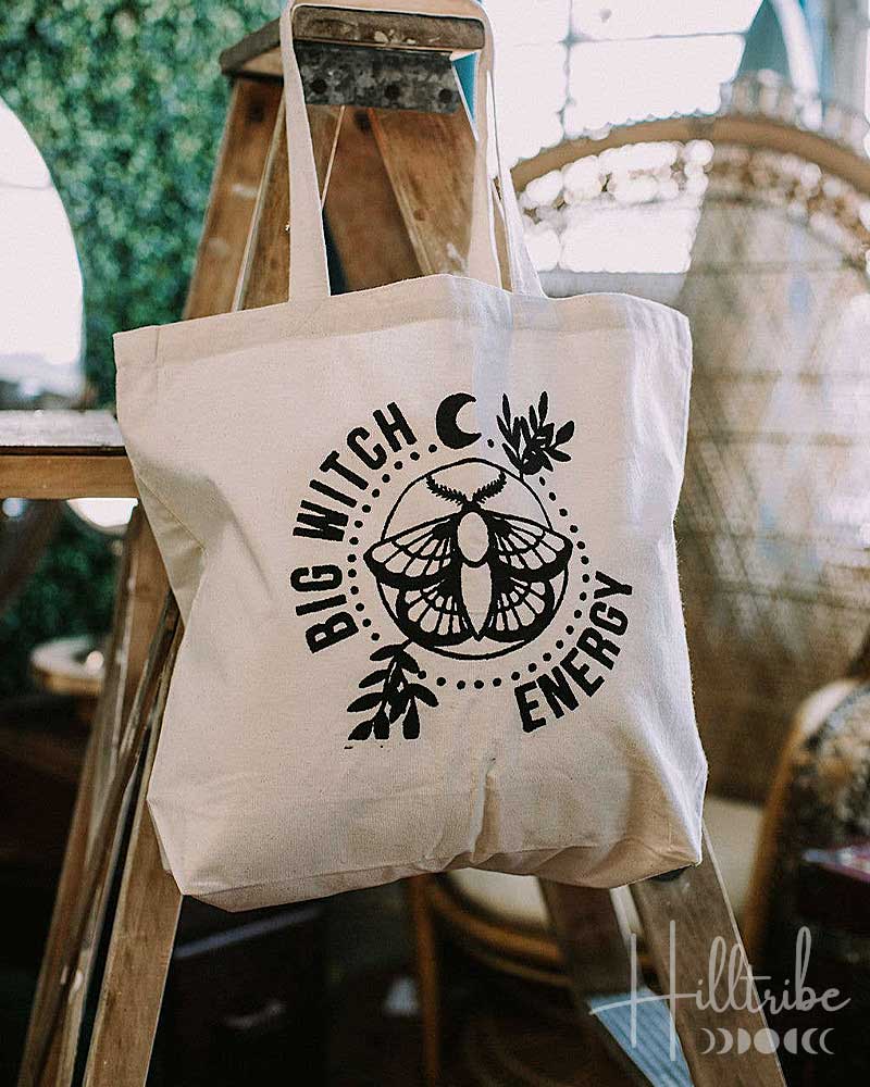 Tote bag with 'Big Witch Energy' design on a wooden ladder