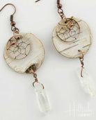Pair of earrings with circular design and crystal-like elements on a white background