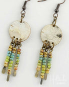 Pair of earrings with round metallic discs and bead chains on a white background