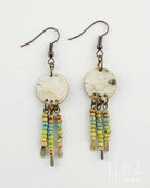 Pair of earrings with circular metal discs and bead chains on a white background