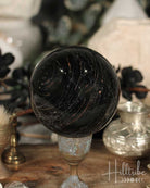 Black Tourmaline sphere on a stand with a blurred background