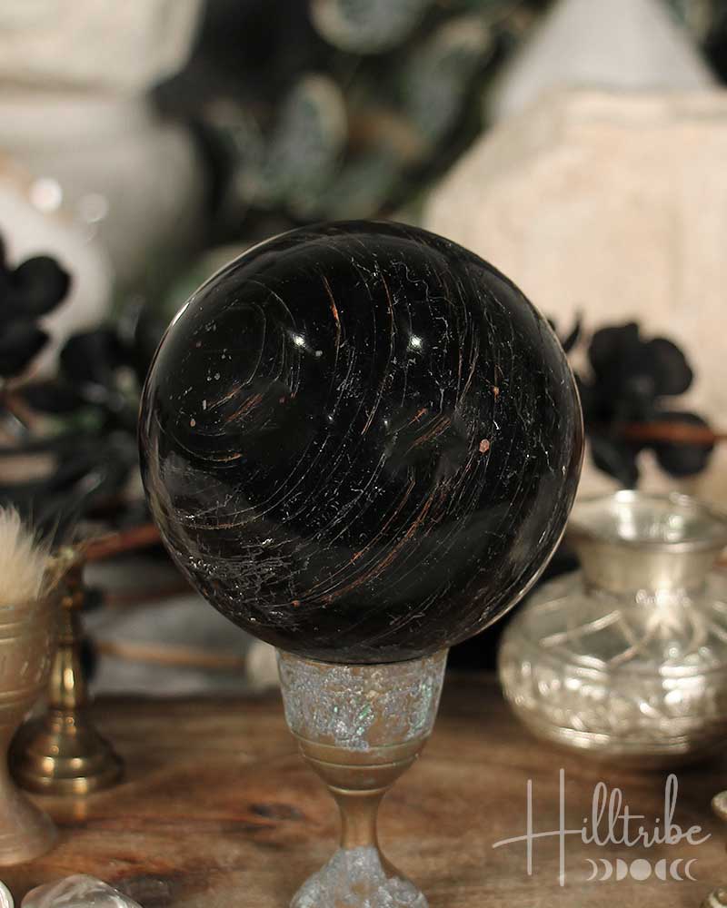 Black Tourmaline sphere on a stand with a blurred background