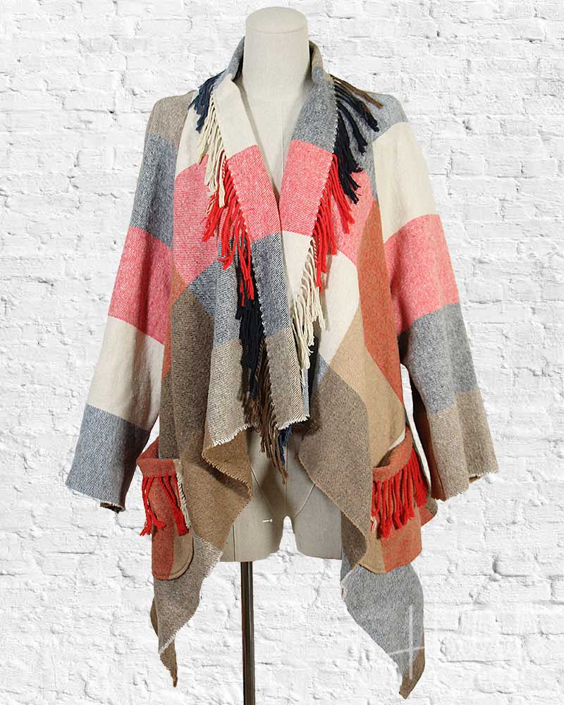 Colorful striped scarf with fringes on a mannequin against a white brick wall.