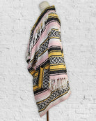 Colorful patterned shawl on a mannequin against a white textured background