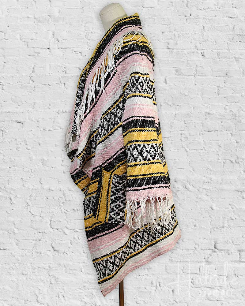 Colorful patterned shawl on a mannequin against a white textured background