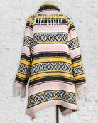 Striped patterned jacket with fringes on a white brick wall background