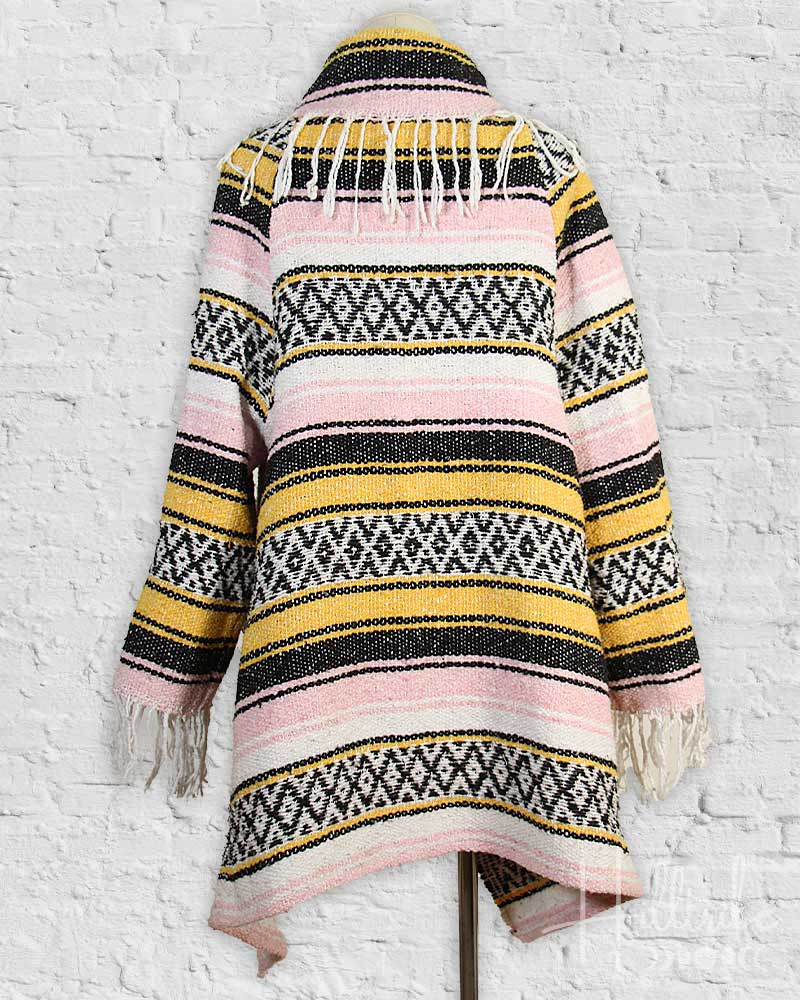 Striped patterned jacket with fringes on a white brick wall background