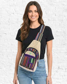 Woman wearing a colorful crossbody bag against a white brick wall