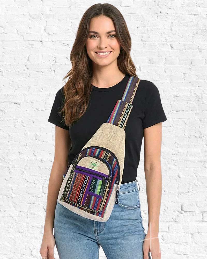 Woman wearing a colorful crossbody bag against a white brick wall